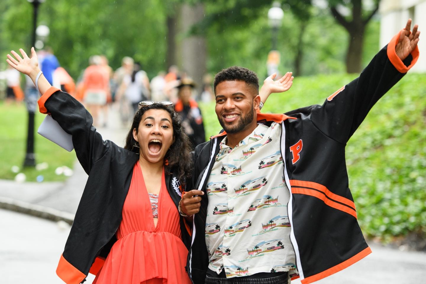 Two young alumni with arms in air in celebratory fashion.