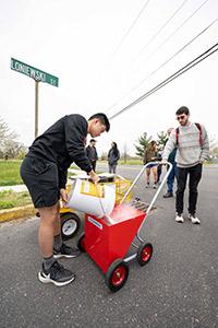 Anlon Zhu, a student in computer science, pours blue-tinted, water-soluble chalk into a liner, which participants in the High Water Line: New Jersey 