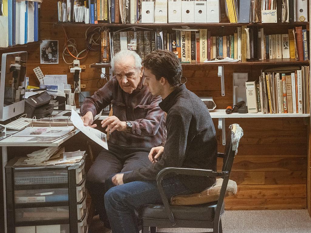 Jordan Salama and his grandfather look over the family archives in a basement office.