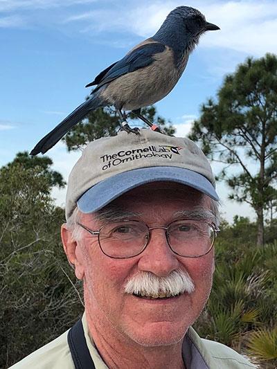 John Fitzpatrick with a blue scrub-jay perched on his ballcap