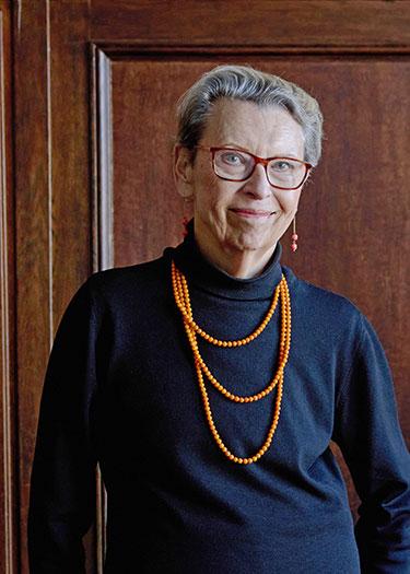 A woman wearing a black shirt and an orange necklace smiles