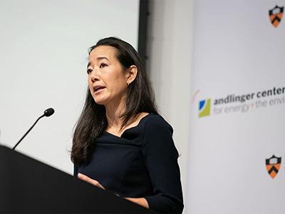 A dark-haired woman speaks at a podium.