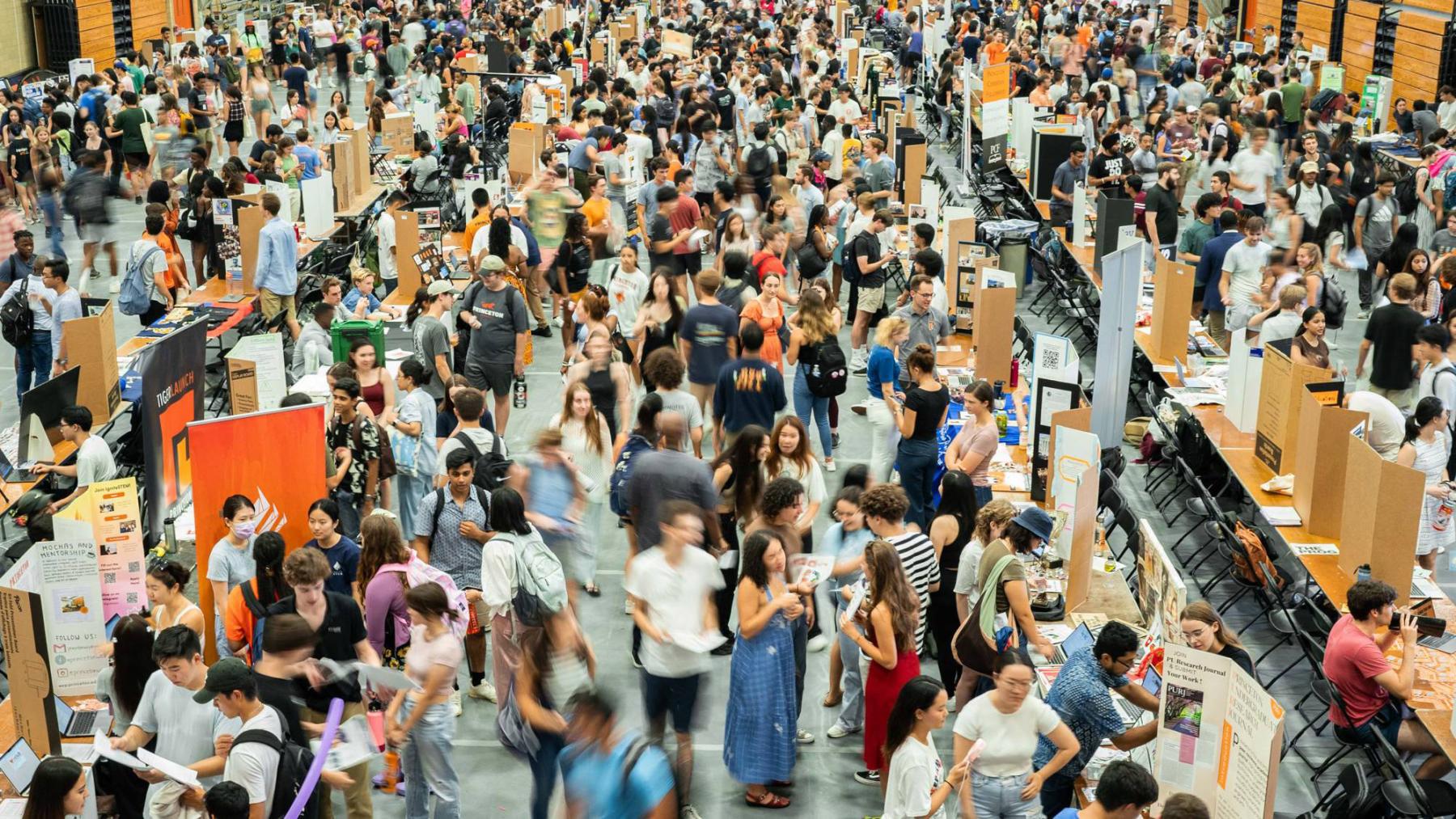 A large hall crowded with students visiting tables for signing up for activities.