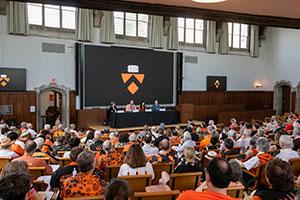 Alumni are seated in a classroom where panelists are seated at the podium