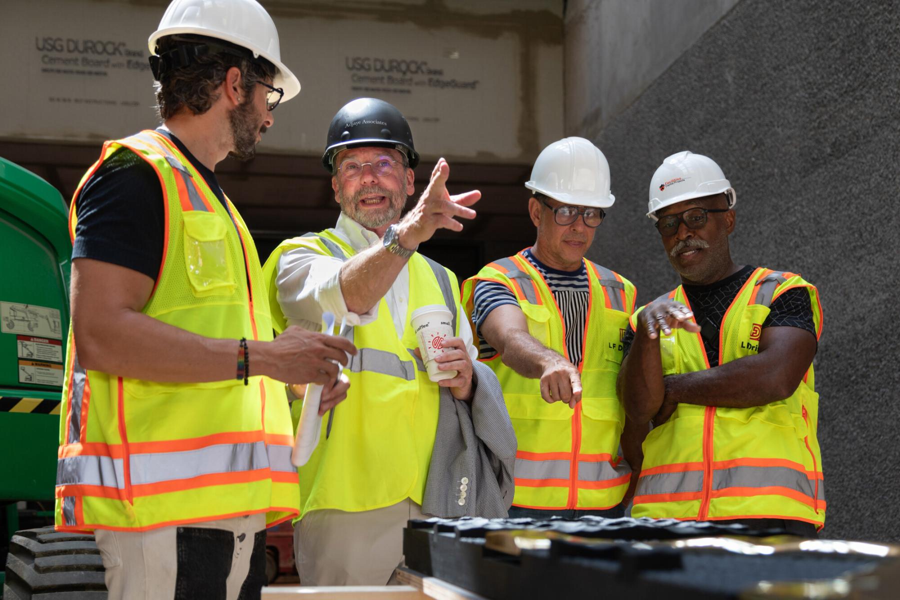 James Steward, wearing a hard hat, discusses the construction of the new art museum with artists and workers at the Art Museum