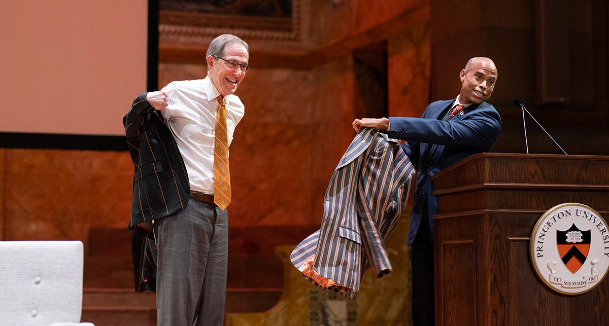 Christopher Eisgruber grins while he tries on his new APGA blazer, a gift from Laurence Latimer.