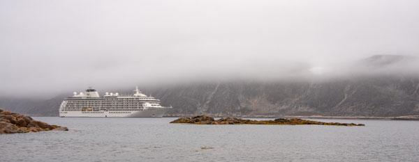 A cruise ship in water with a fog over it