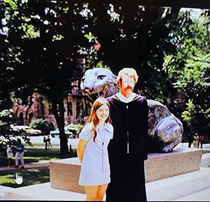 Bonnie Hewson and Chuck Marboe in front of a tiger statue; he is wearing a graduation gown