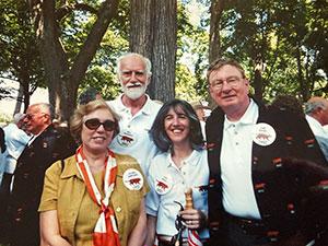 Four people stand outside wearing buttons with Tigers on them; Ada and Tom Deuel are at right
